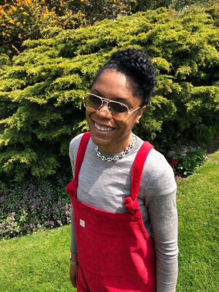 Iesha Small in red dungarees smiling